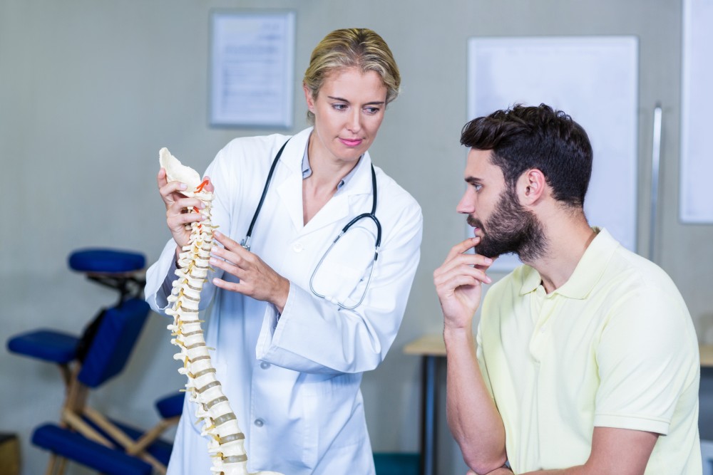 physiotherapist explaining spine model to patient